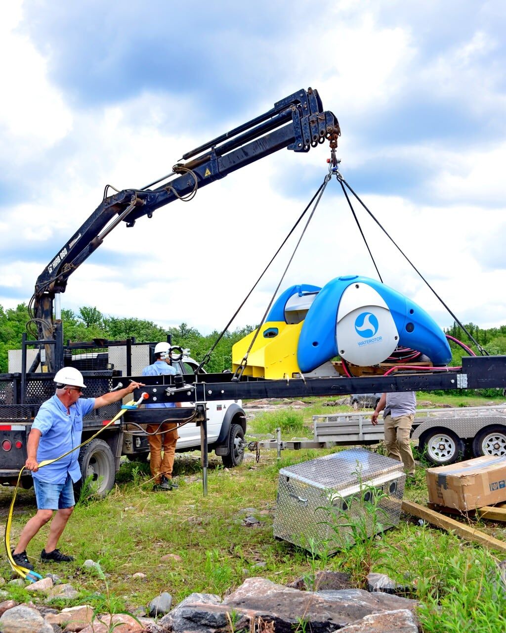 A truck-mounted crane lifts a Waterotor unit onto a trailer