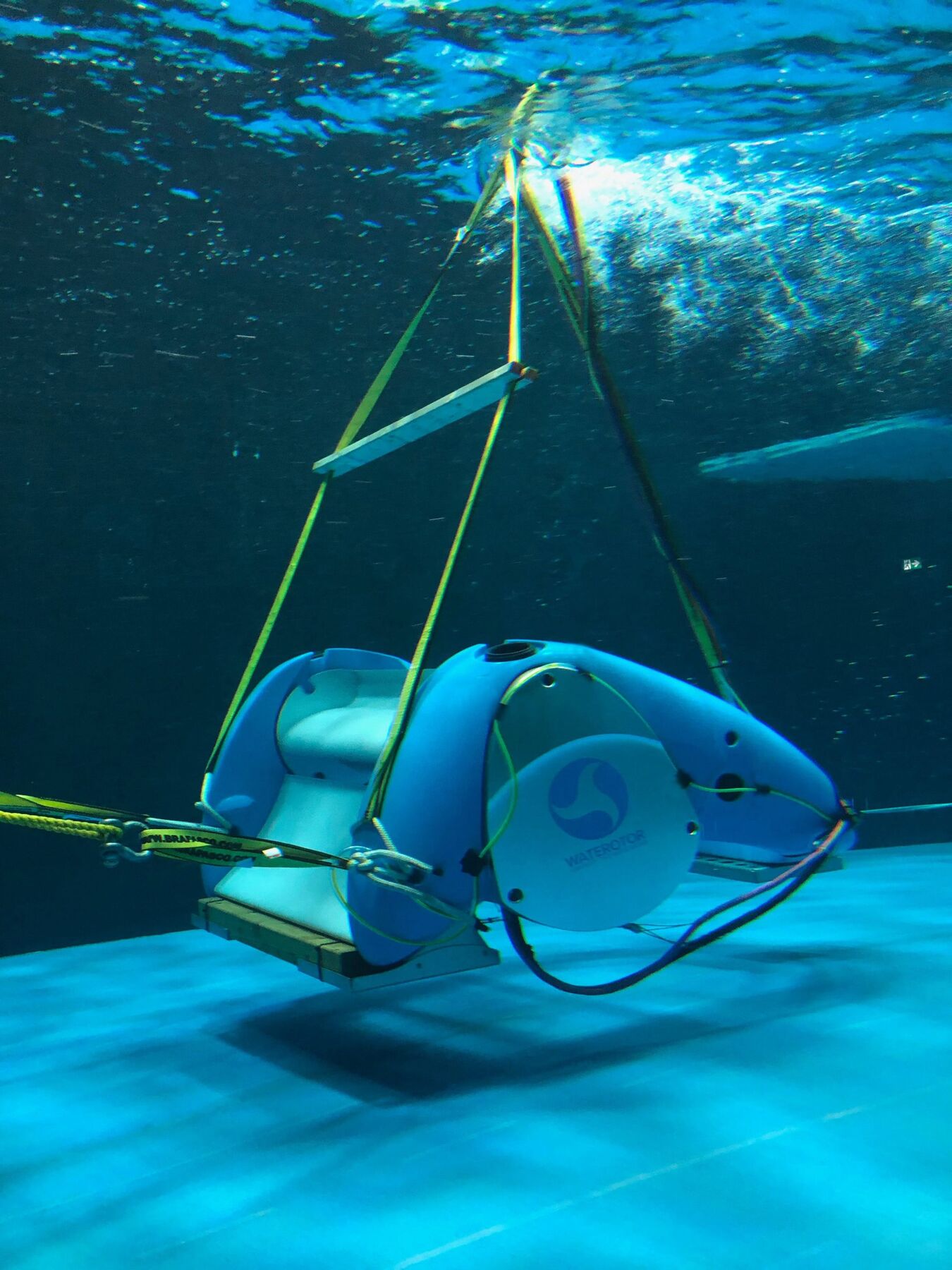 A blue and white Waterotor unit suspended underwater from a lifting frame